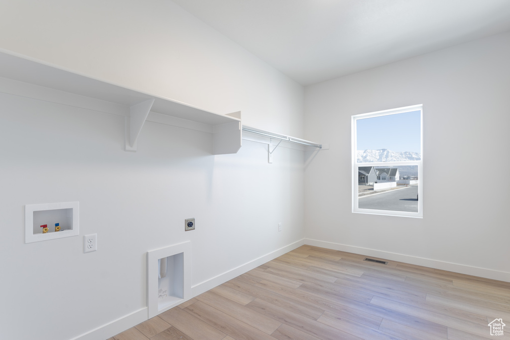 Clothes washing area featuring hookup for a washing machine, electric dryer hookup, and light hardwood / wood-style floors