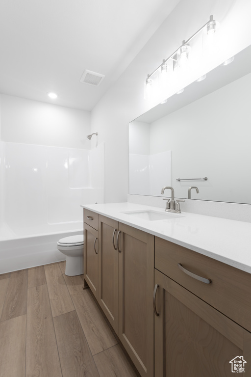 Full bathroom featuring hardwood / wood-style flooring, vanity, toilet, and bathing tub / shower combination