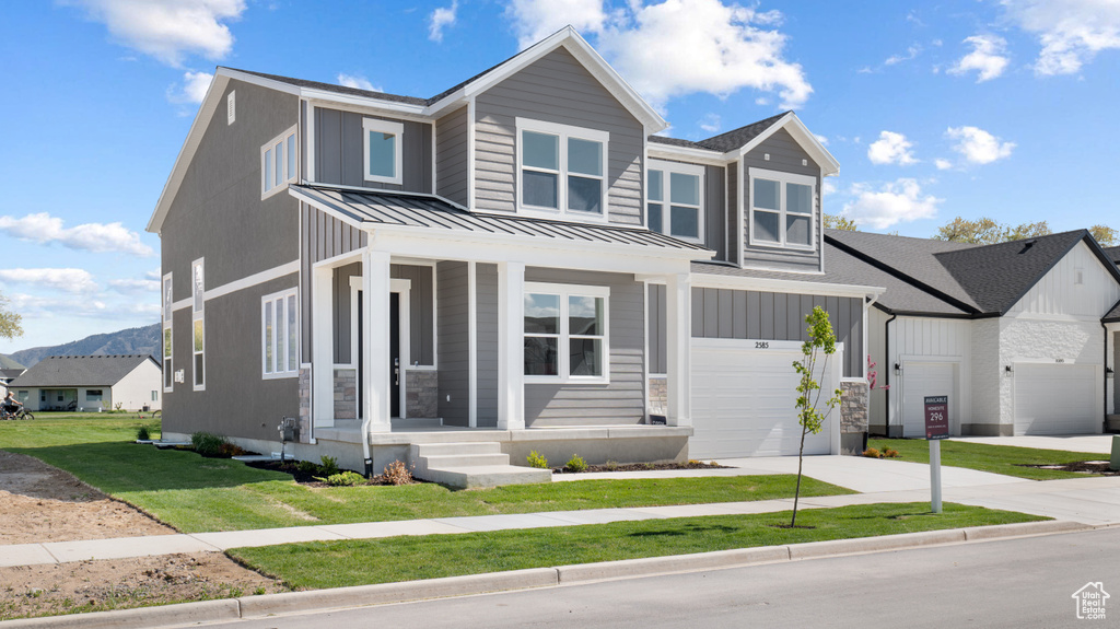 View of front facade featuring a standing seam roof, driveway, covered porch, a front lawn, and metal roof