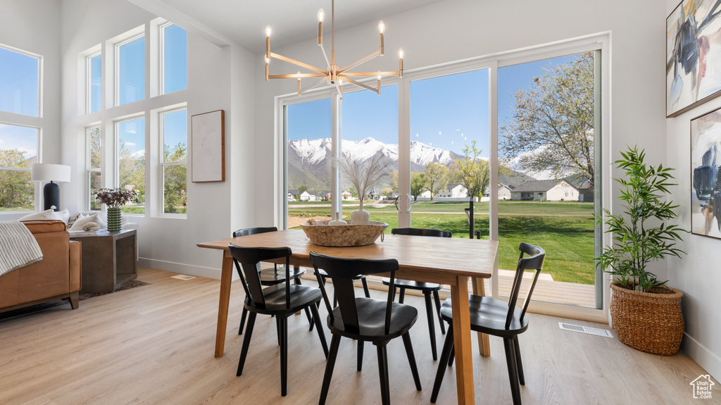 Dining room featuring a chandelier, light wood-type flooring, baseboards, and a mountain view