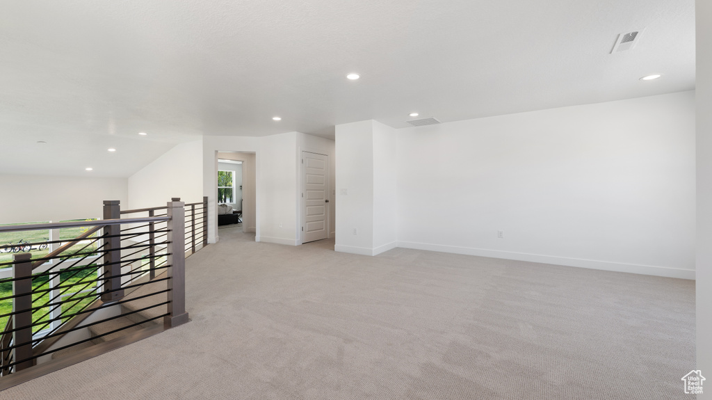 Additional living space with recessed lighting, light carpet, and baseboards