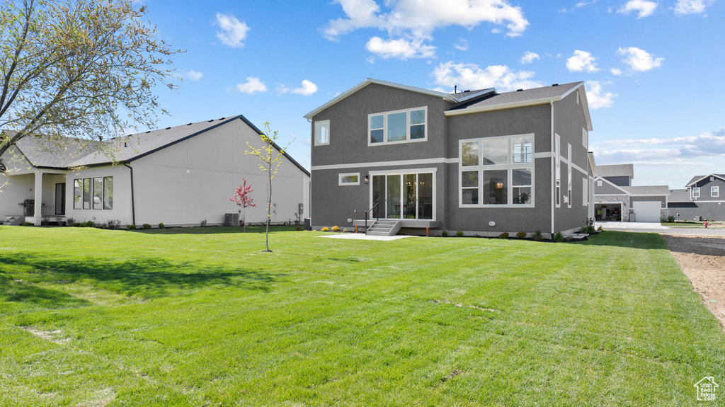 Back of property featuring a yard, stucco siding, and central AC