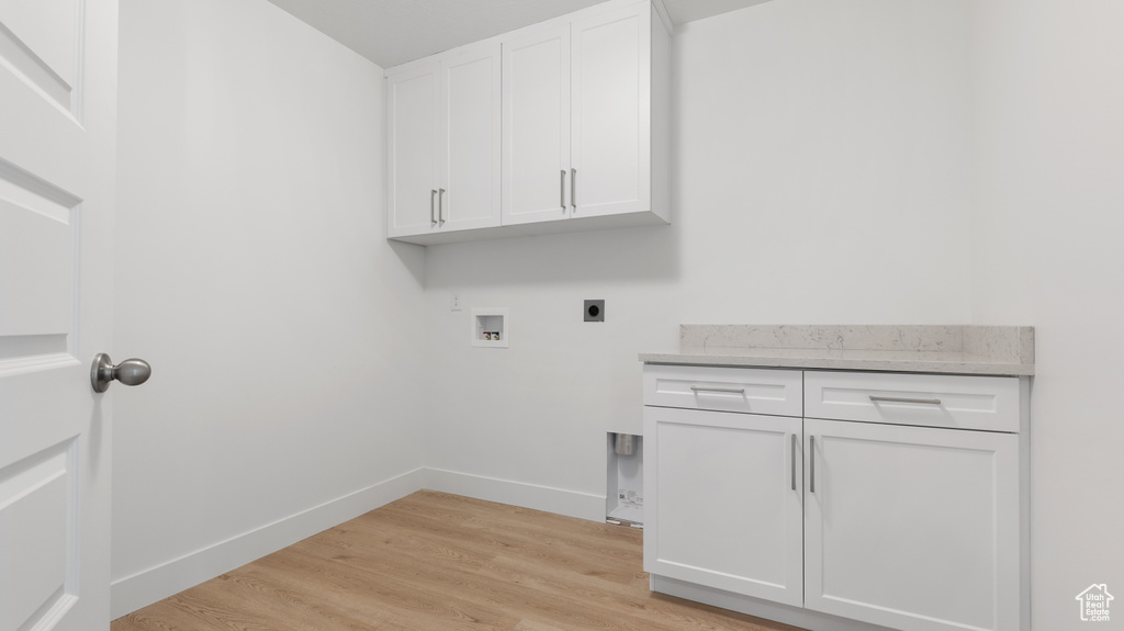Laundry area featuring electric dryer hookup, cabinet space, hookup for a washing machine, light wood finished floors, and baseboards