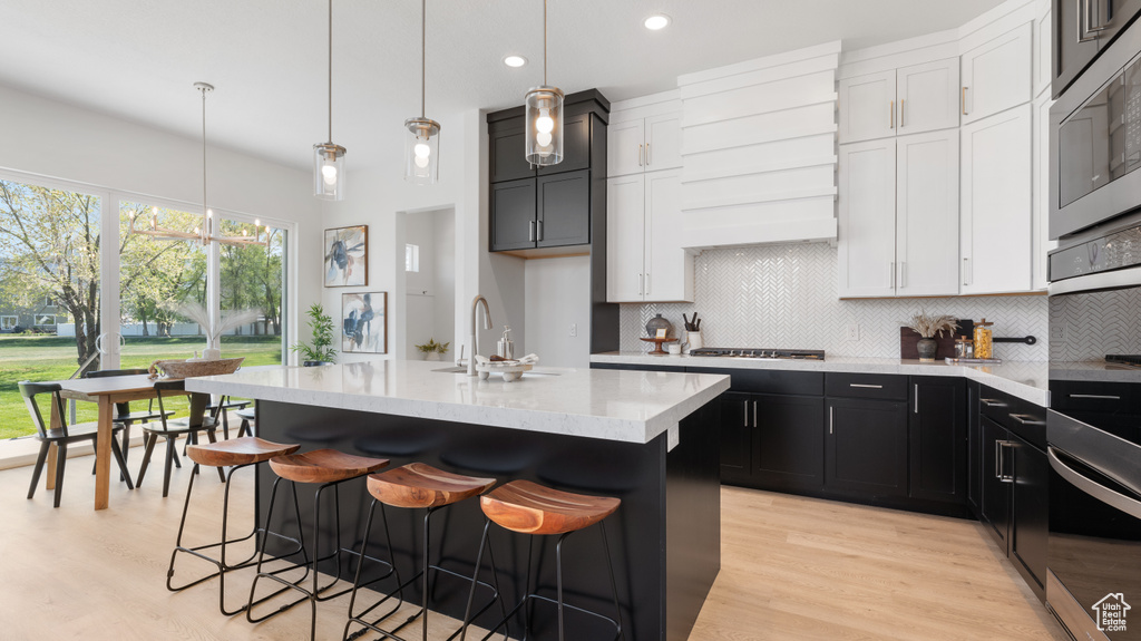 Kitchen featuring decorative backsplash, a sink, healthy amount of natural light, light wood-type flooring, and recessed lighting