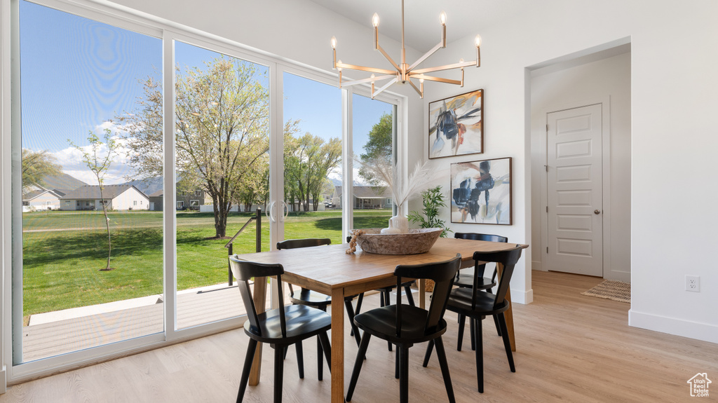 Dining area with a chandelier, light wood finished floors, and baseboards