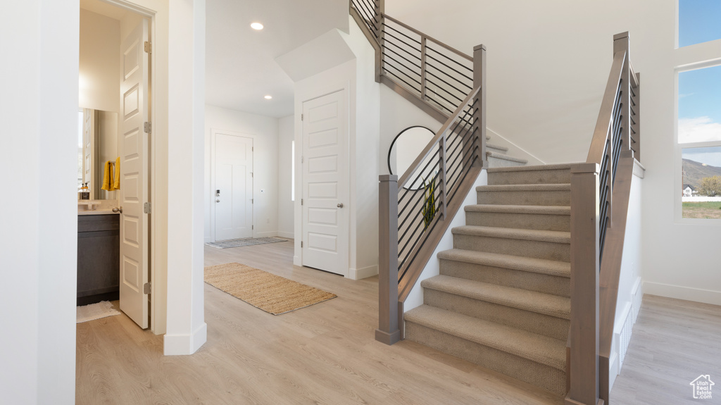 Staircase with wood finished floors, baseboards, and recessed lighting