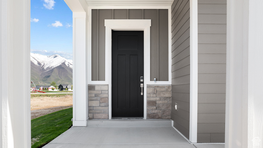 Property entrance with a mountain view, board and batten siding, and stone siding