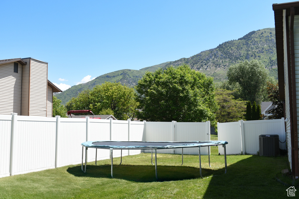 View of yard featuring a trampoline, a mountain view, and central AC unit