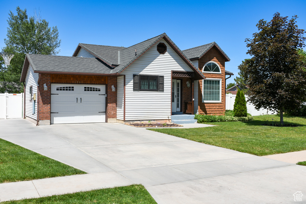 View of front of property with an attached garage, driveway, and a shingled roof