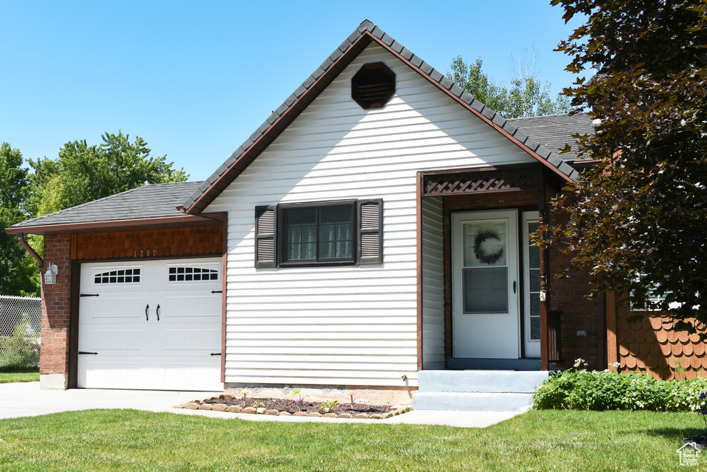 View of front of home with a garage, concrete driveway, and a front lawn
