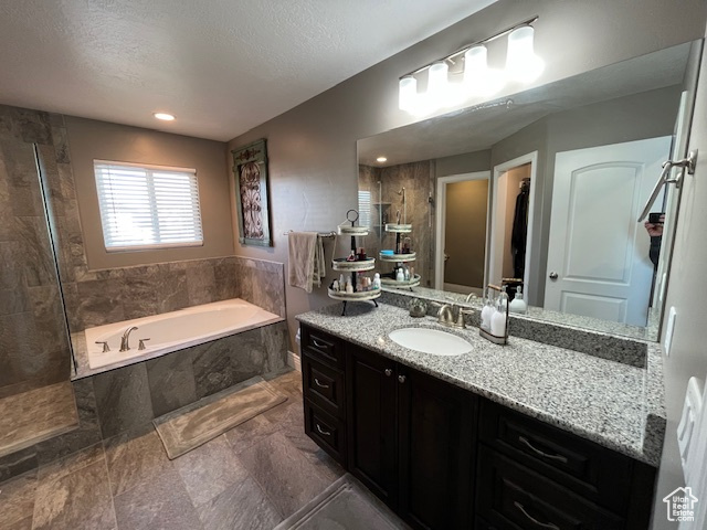 Full bath featuring a tile shower, vanity, a textured ceiling, and a garden tub