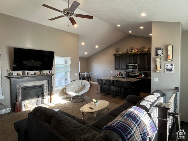Living area with baseboards, ceiling fan, a fireplace, recessed lighting, and lofted ceiling