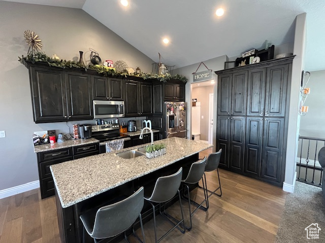 Kitchen featuring light wood-type flooring, a kitchen island with sink, a kitchen bar, appliances with stainless steel finishes, and a sink