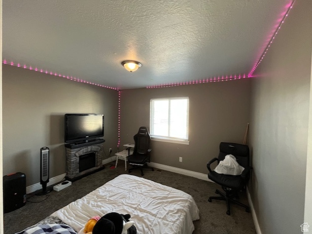 Bedroom with a fireplace, a textured ceiling, baseboards, and carpet floors
