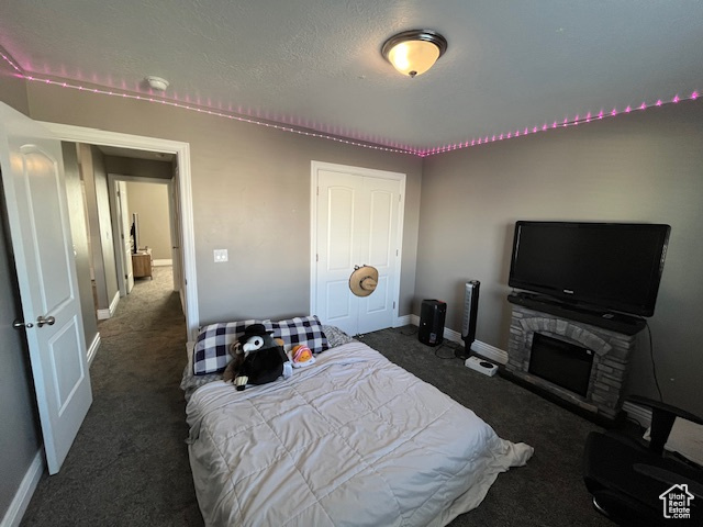 Bedroom with a closet, carpet flooring, a stone fireplace, and baseboards