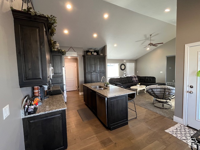 Kitchen with dishwasher, a sink, ceiling fan, wood finished floors, and a center island with sink