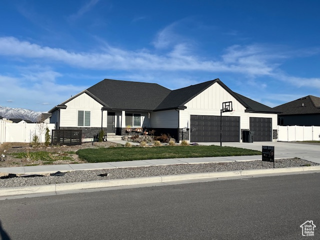 Modern inspired farmhouse featuring an attached garage, board and batten siding, concrete driveway, and fence