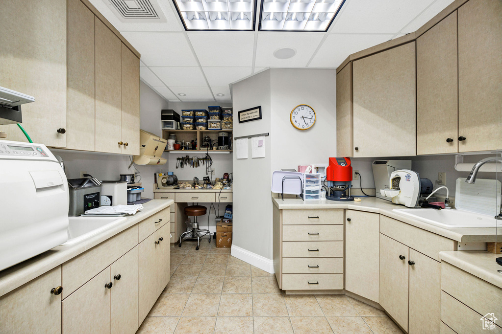 Kitchen with sink, a paneled ceiling, light brown cabinetry, and light tile patterned floors