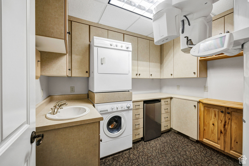 Washroom with stacked washer / drying machine and dark flooring
