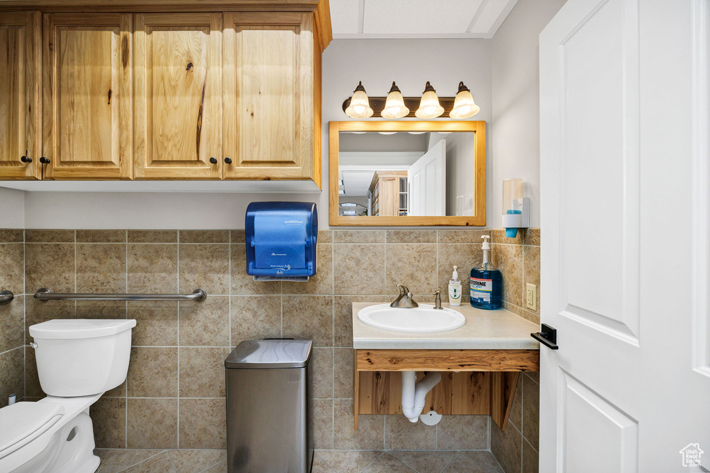 Bathroom with toilet, sink, and tile walls