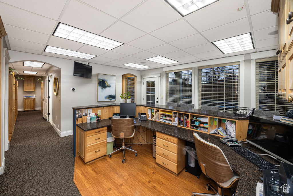 Office with light hardwood / wood-style flooring and a paneled ceiling