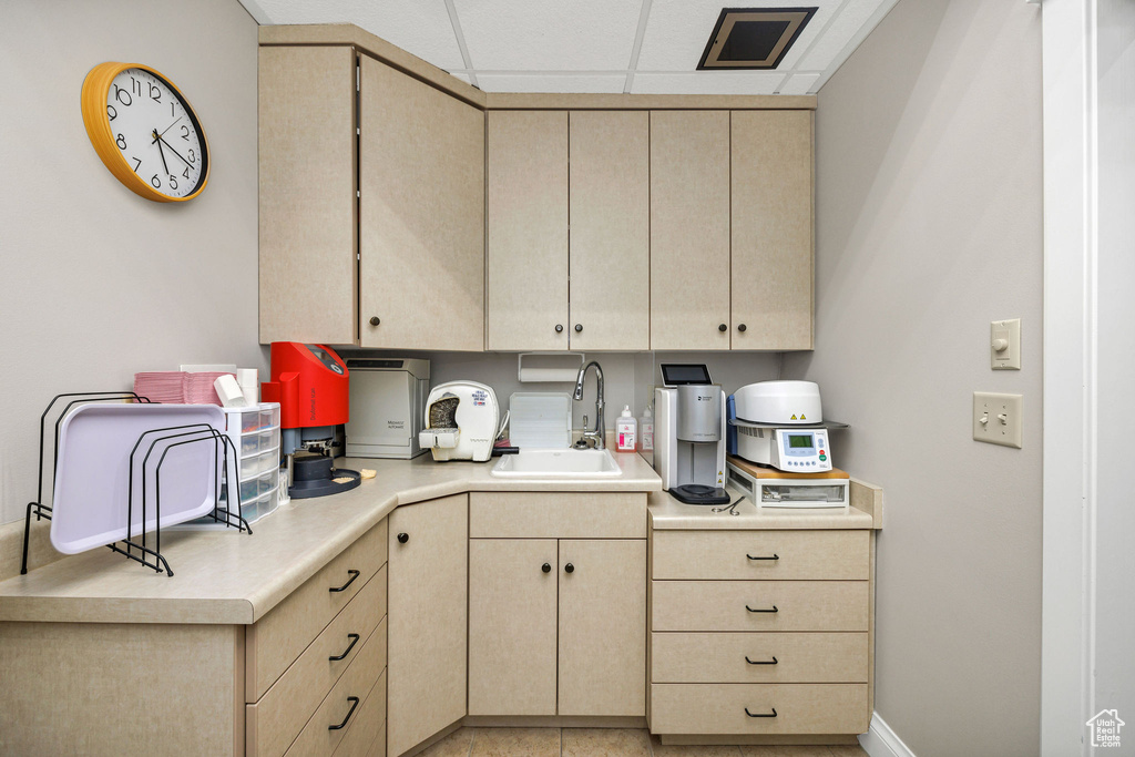 Kitchen with a drop ceiling, sink, and light brown cabinets