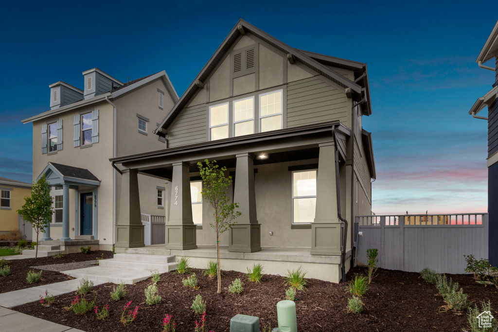 View of front facade with covered porch and stucco siding