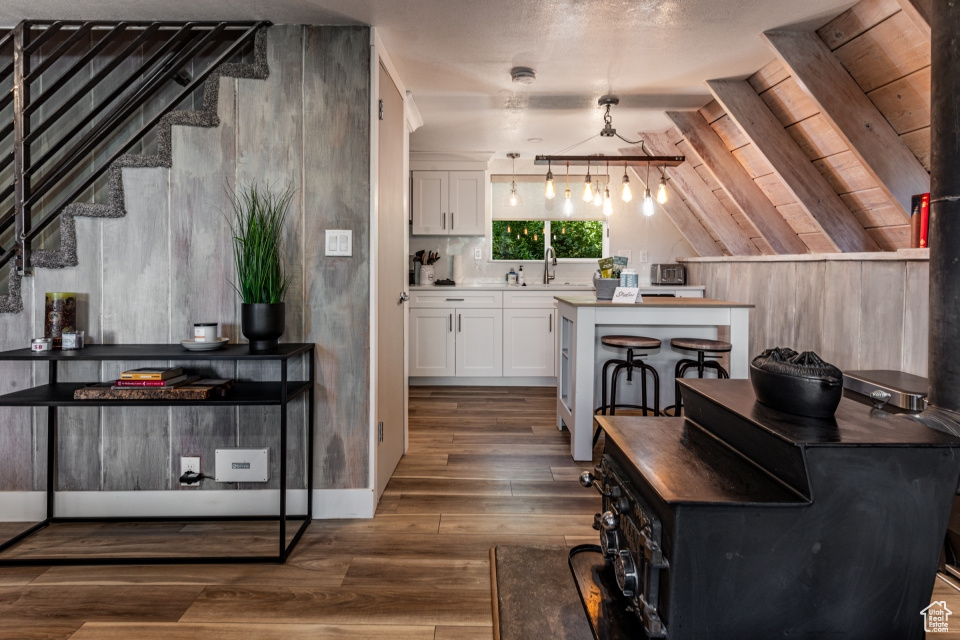 Kitchen with lofted ceiling, sink, hanging light fixtures, white cabinets, and dark hardwood / wood-style flooring