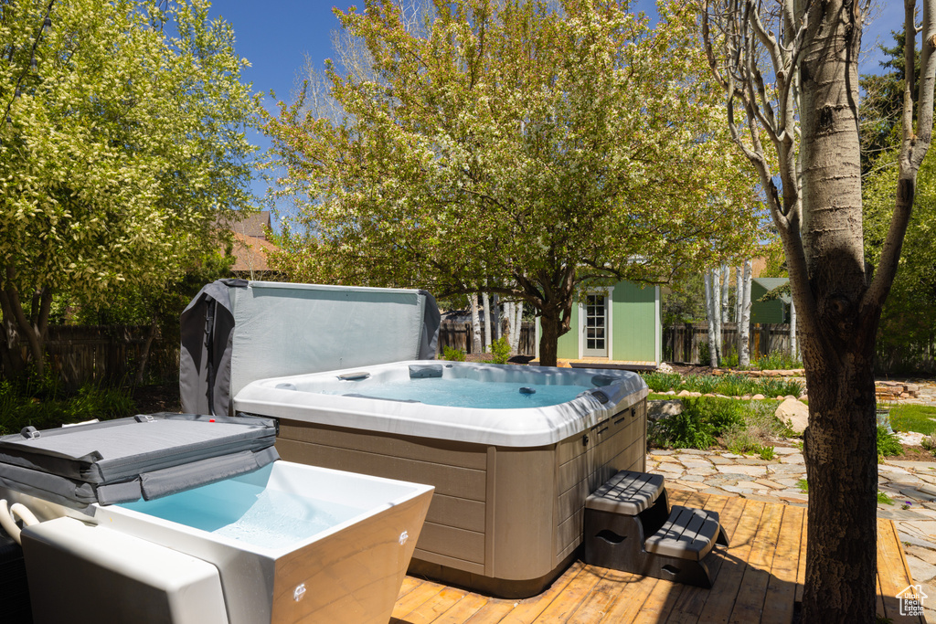 Deck featuring a hot tub and an outbuilding
