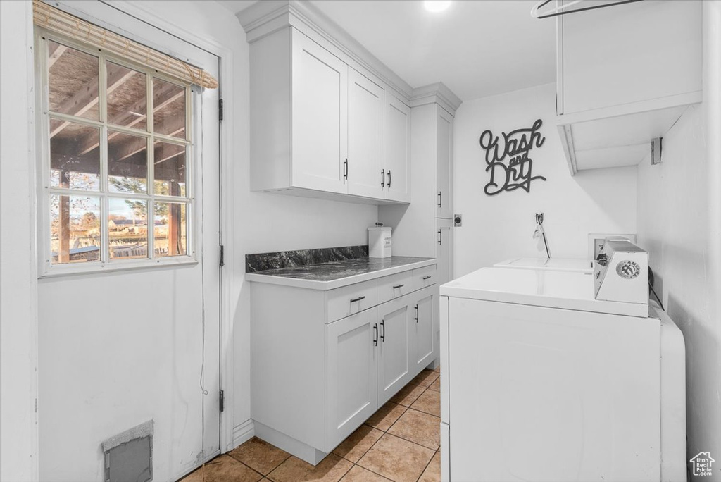 Washroom featuring washer and dryer, cabinets, and light tile patterned flooring