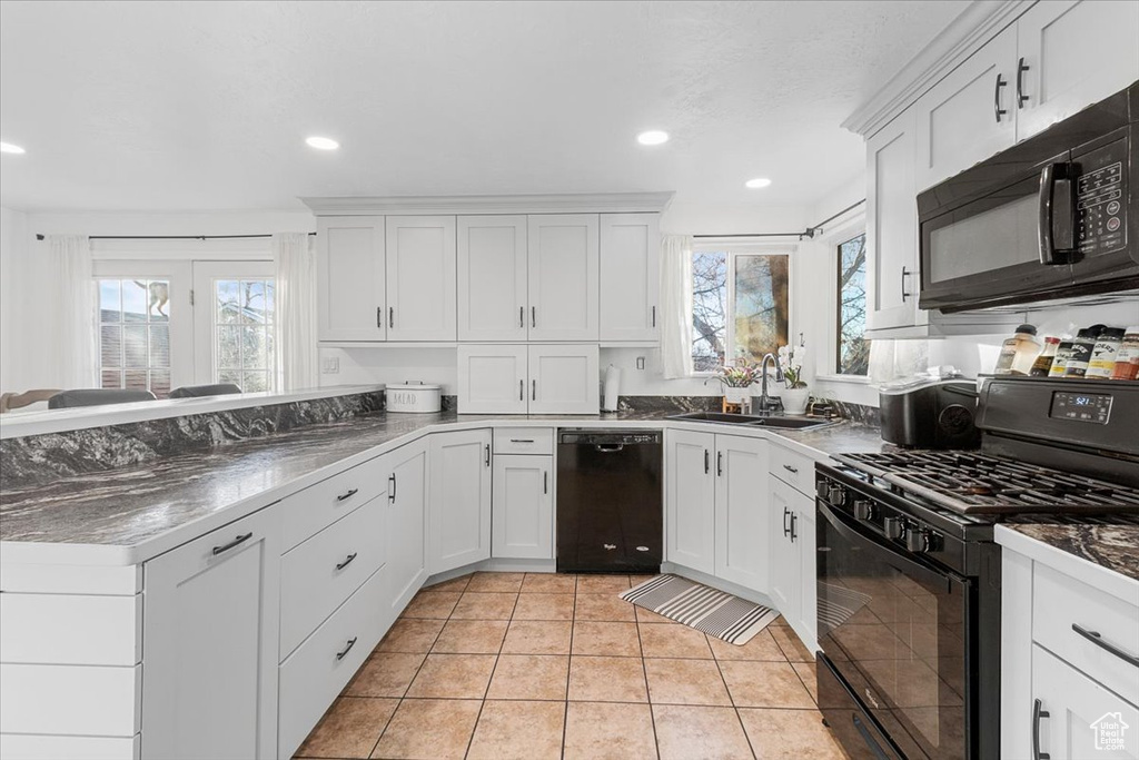 Kitchen with white cabinetry, a healthy amount of sunlight, sink, and black appliances