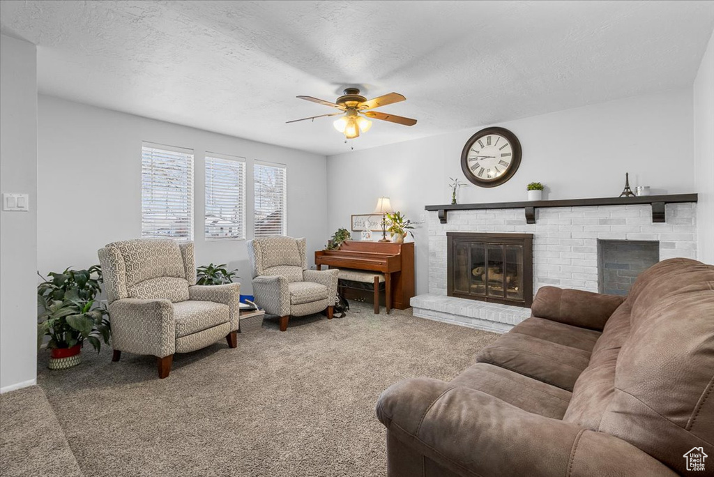 Carpeted living room featuring ceiling fan, a brick fireplace, and a textured ceiling