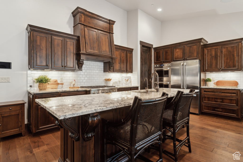 Kitchen featuring a kitchen island with sink, sink, a breakfast bar area, and stainless steel appliances