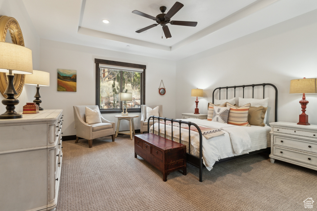 Carpeted bedroom with ceiling fan and a raised ceiling