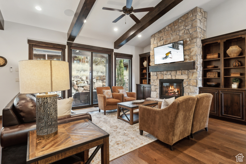 Living room with lofted ceiling with beams, a stone fireplace, dark hardwood / wood-style floors, and ceiling fan