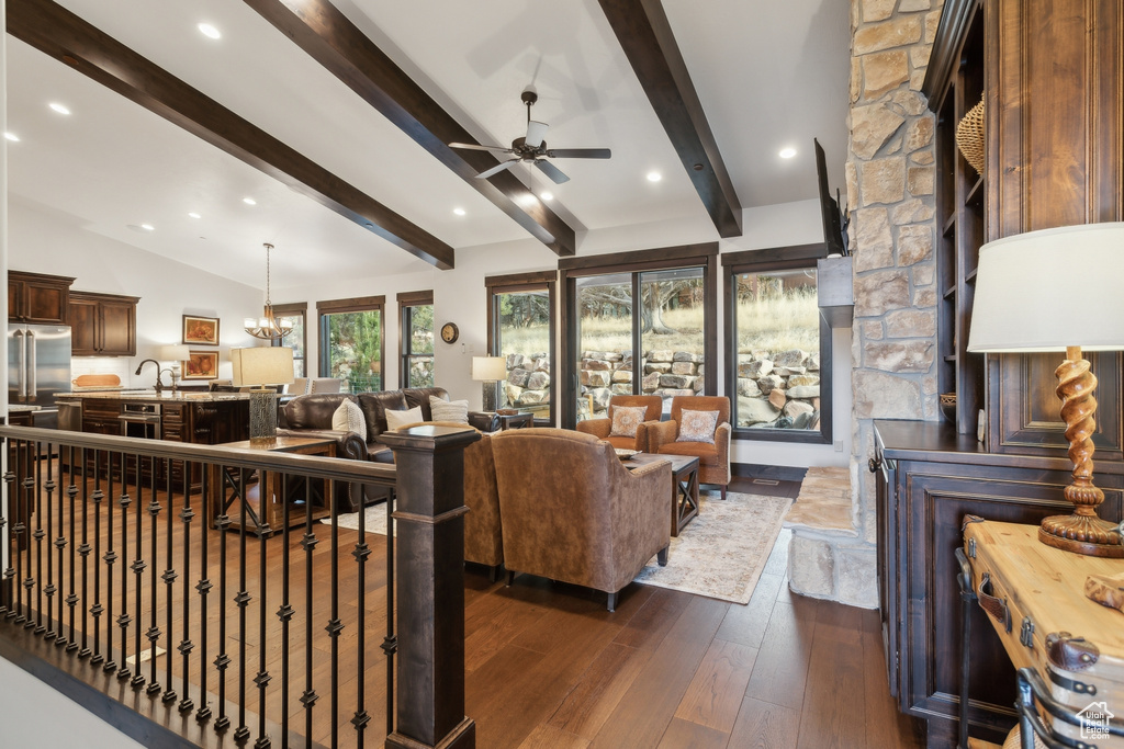 Living room featuring lofted ceiling with beams, dark hardwood / wood-style floors, and ceiling fan with notable chandelier