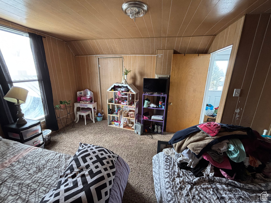Bedroom featuring vaulted ceiling, carpet floors, wooden ceiling, and wooden walls