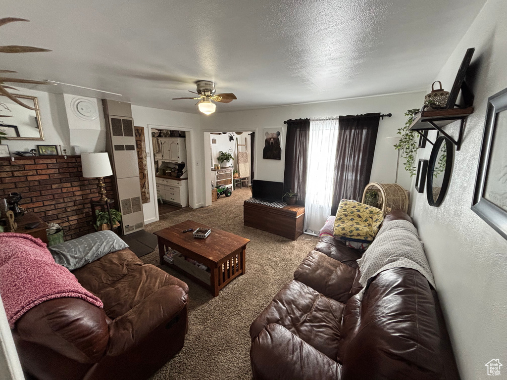Carpeted living room with ceiling fan and a textured ceiling