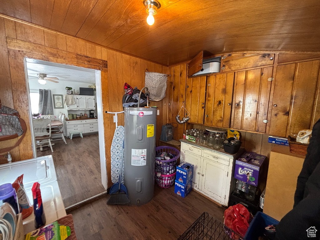 Kitchen featuring wood ceiling, dark wood-type flooring, water heater, and wood walls