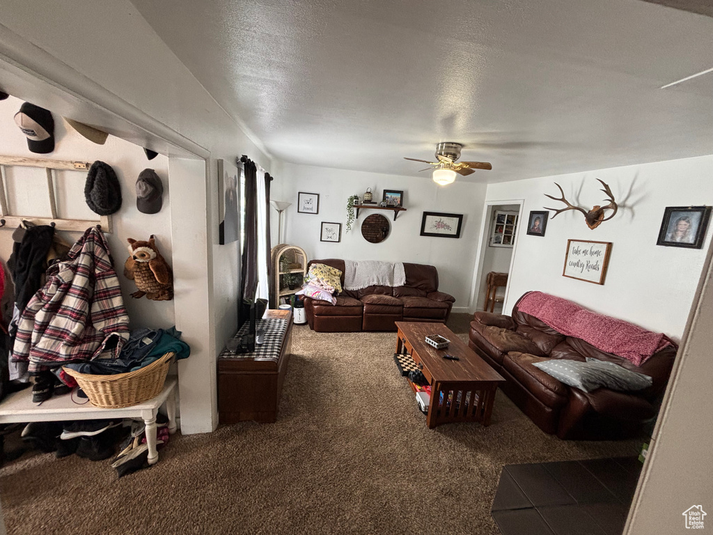Carpeted living room featuring ceiling fan and a textured ceiling