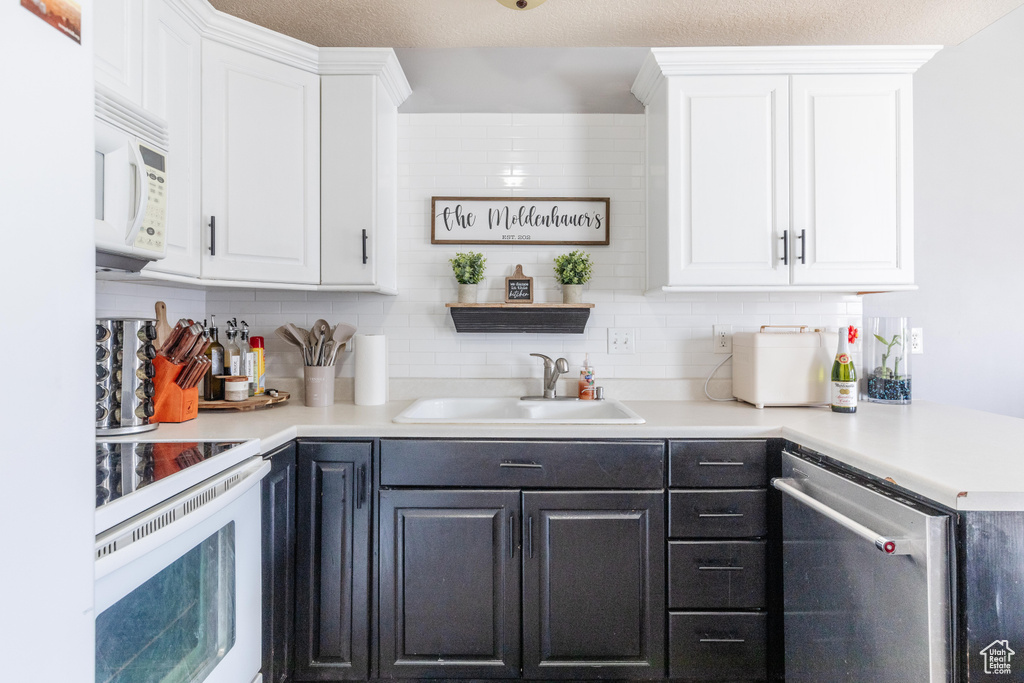 Bar featuring white cabinetry, sink, white appliances, and backsplash