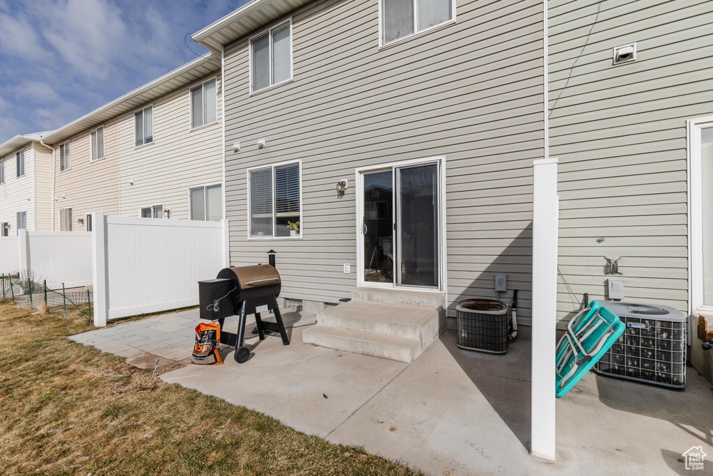 Rear view of house with cooling unit, a yard, and a patio