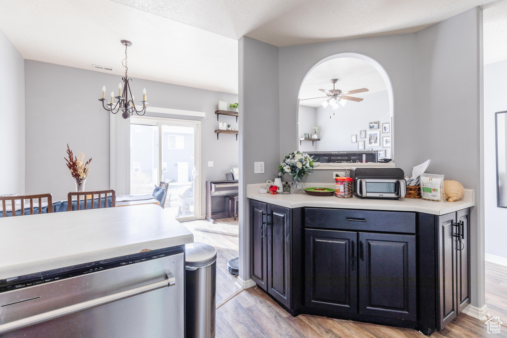 Kitchen with ceiling fan with notable chandelier, pendant lighting, stainless steel dishwasher, and light hardwood / wood-style floors