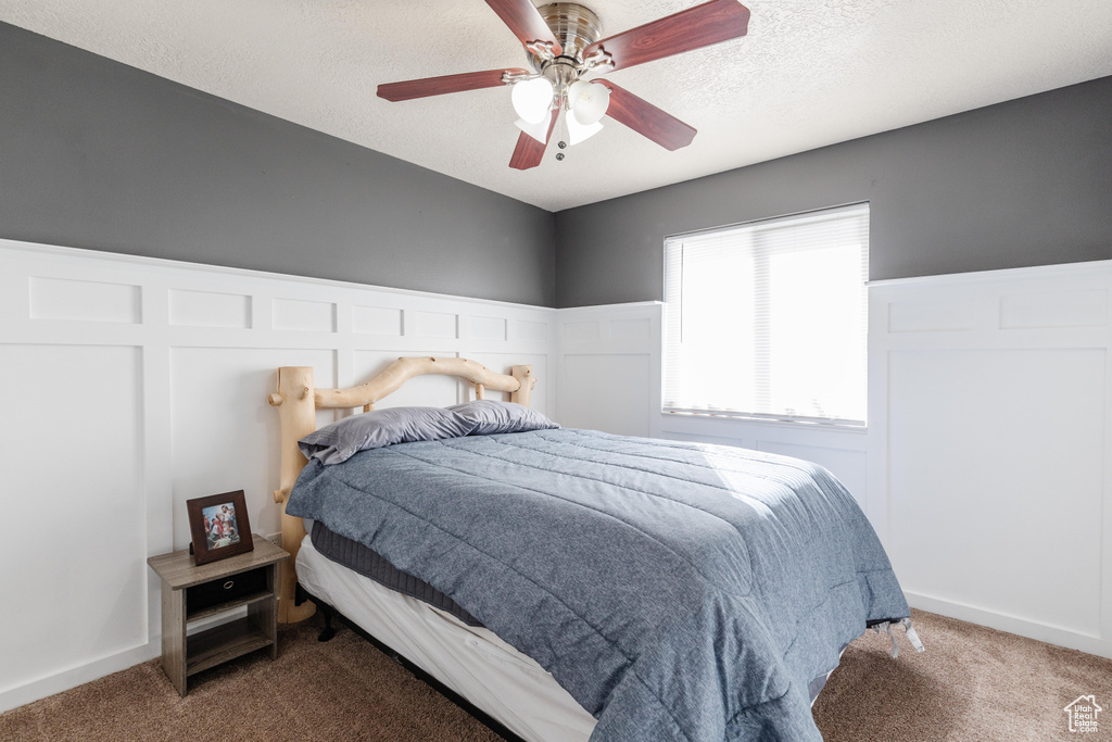 Carpeted bedroom featuring ceiling fan and a textured ceiling