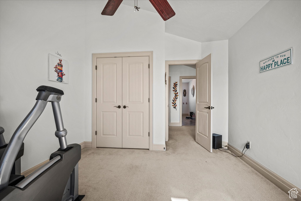 Exercise room with ceiling fan, lofted ceiling, and light carpet