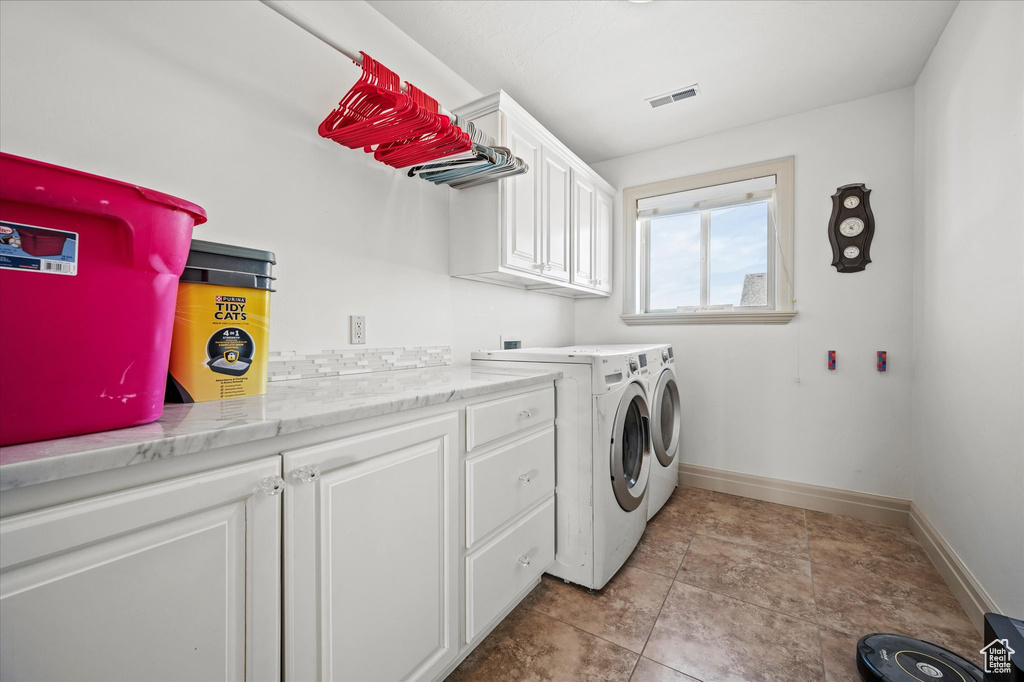 Laundry room featuring separate washer and dryer, light tile patterned floors, and cabinets