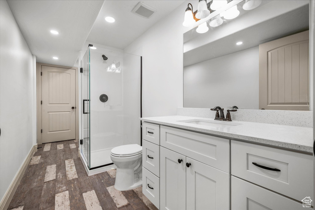 Bathroom with toilet, vanity, a shower with door, and hardwood / wood-style floors