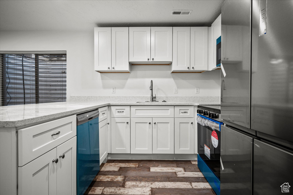 Kitchen featuring stainless steel appliances, dark hardwood / wood-style flooring, sink, and white cabinets