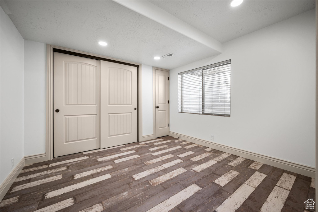 Unfurnished bedroom featuring a closet, dark hardwood / wood-style floors, and a textured ceiling