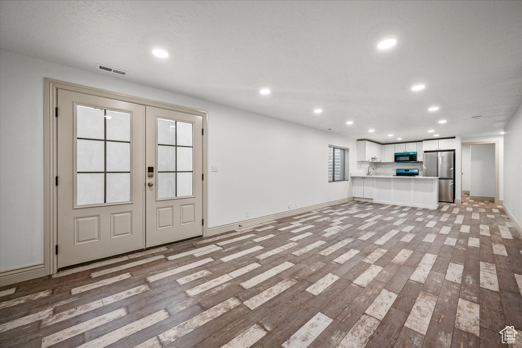 Unfurnished living room with french doors and light wood-type flooring